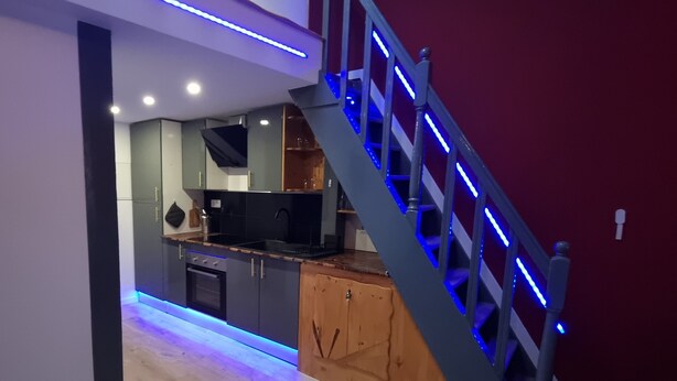Una cocina moderna con horno integrado, armarios de madera y encimera negra.
