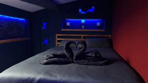Una habitación de hotel con cama, un panel de luz en la pared y una pared decorativa con figuras iluminadas.