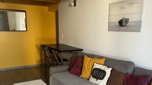 Un soggiorno moderno con un divano grigio, un tavolino da caffè bianco e un soffitto in legno.