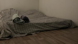 Una stanza piccola, scarsamente illuminata, con un letto singolo rivestito da una coperta fantasia.