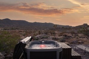 A hot tub in a desert landscape with mountains in the background.