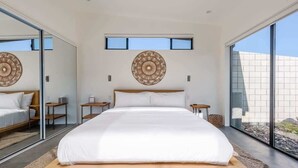 Une chambre moderne avec un grand lit, deux tables de chevet, un élément de décoration circulaire fixé au mur et une grande fenêtre.