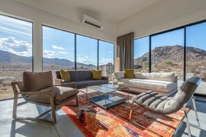 Un salon moderne avec de grandes fenêtres, un canapé, un fauteuil et une table basse.