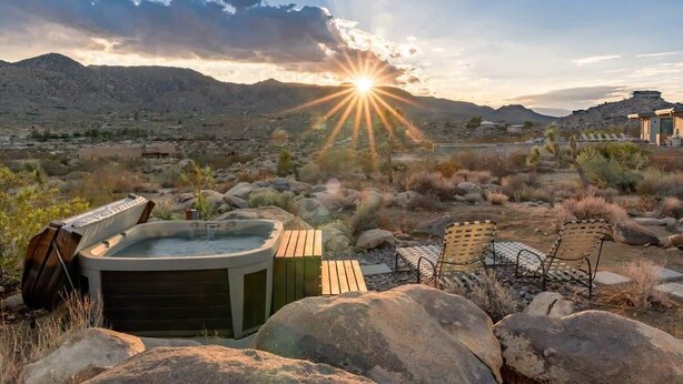 Un bain à remous, un espace salon extérieur et un paysage montagneux en toile de fond.