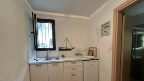 A compact kitchen with white cabinets, a sink, a small dish rack, and a refrigerator. - Maisonette With Garden Under the Elani Pines (Kassandra)