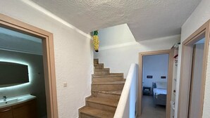 A staircase leading to a bedroom with a bed, a nightstand, and a dresser. - Maisonette With Garden Under the Elani Pines (Kassandra)