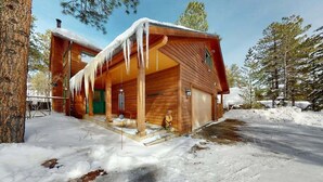 Una baita di legno con veranda, circondata da neve e alberi.