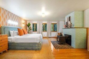 A bedroom with a bed, dresser, and fireplace.