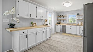 A modern kitchen with white cabinets, a wooden countertop, and a stainless steel refrigerator. - Inlet Paradise A - Your Perfect Coastal Escape! (Murrells Inlet)