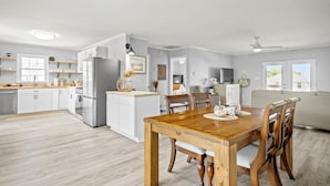 A modern kitchen with white cabinets, a wooden dining table, and a built-in island. - Inlet Paradise A - Your Perfect Coastal Escape! (Murrells Inlet)