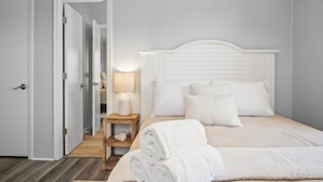 A bedroom with a white headboard, a bedside table with a lamp, and neatly folded towels on the bed. - Inlet Paradise A - Your Perfect Coastal Escape! (Murrells Inlet)