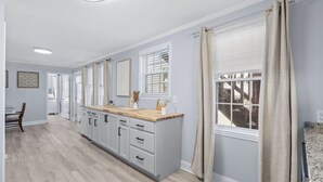 A modern kitchen with a central island, white cabinetry, and a wooden countertop. - Inlet Paradise B Beautiful Condo Walking Distance to Beach! (Murrells Inlet)
