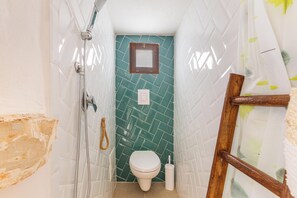 Ein Badezimmer mit Dusche, Toilette und kleinem Fenster.