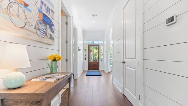 A hallway with a wooden bench, a lamp, and a vase with flowers. - Uncloudy Day hosts 10 guests with a Pool (St Simons Island)