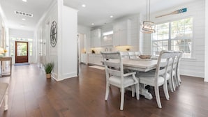A spacious kitchen with white cabinetry, a wooden dining table, and chairs. - Uncloudy Day hosts 10 guests with a Pool (St Simons Island)