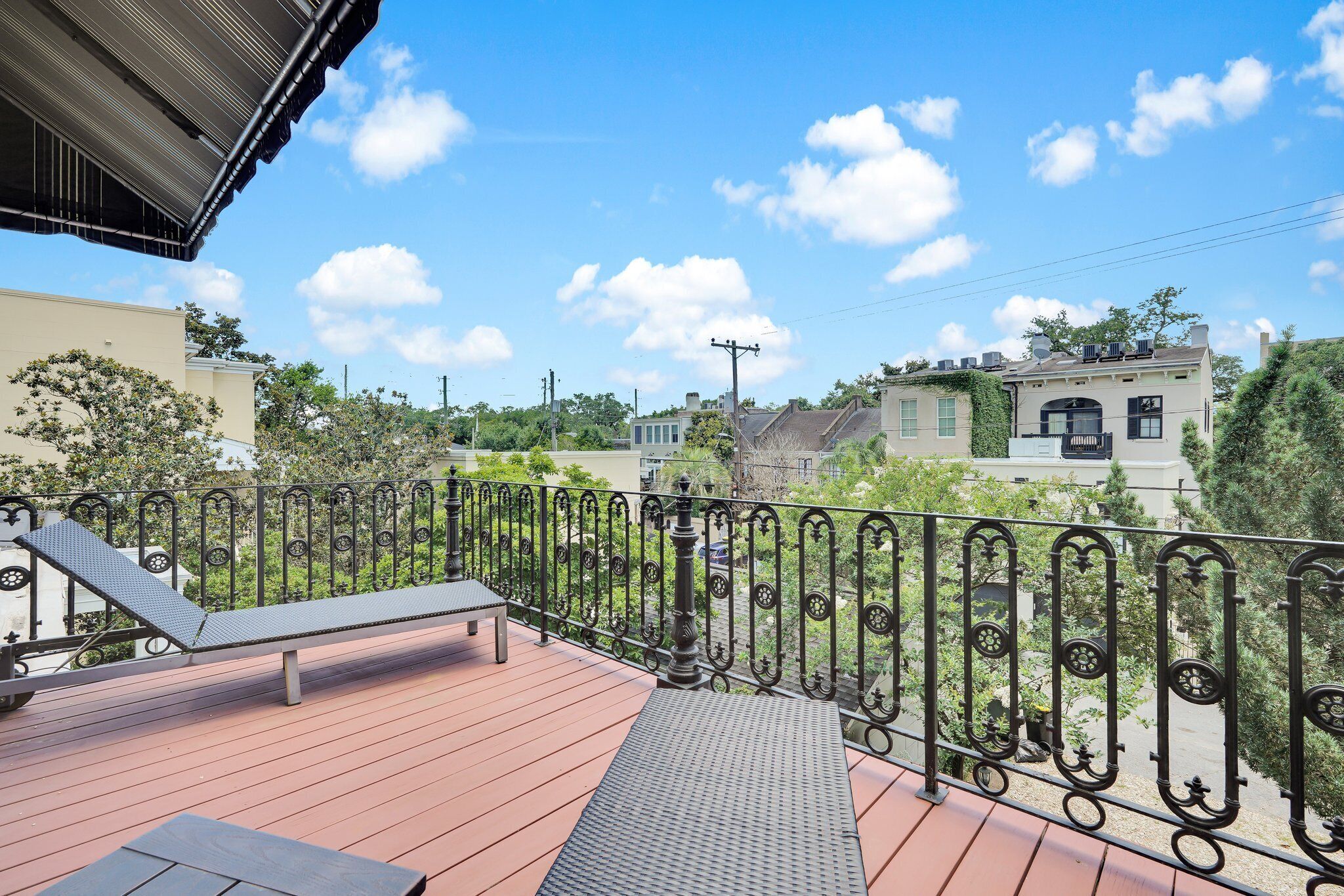 A balcony with a metal railing, a bench, and a view of surrounding buildings.
