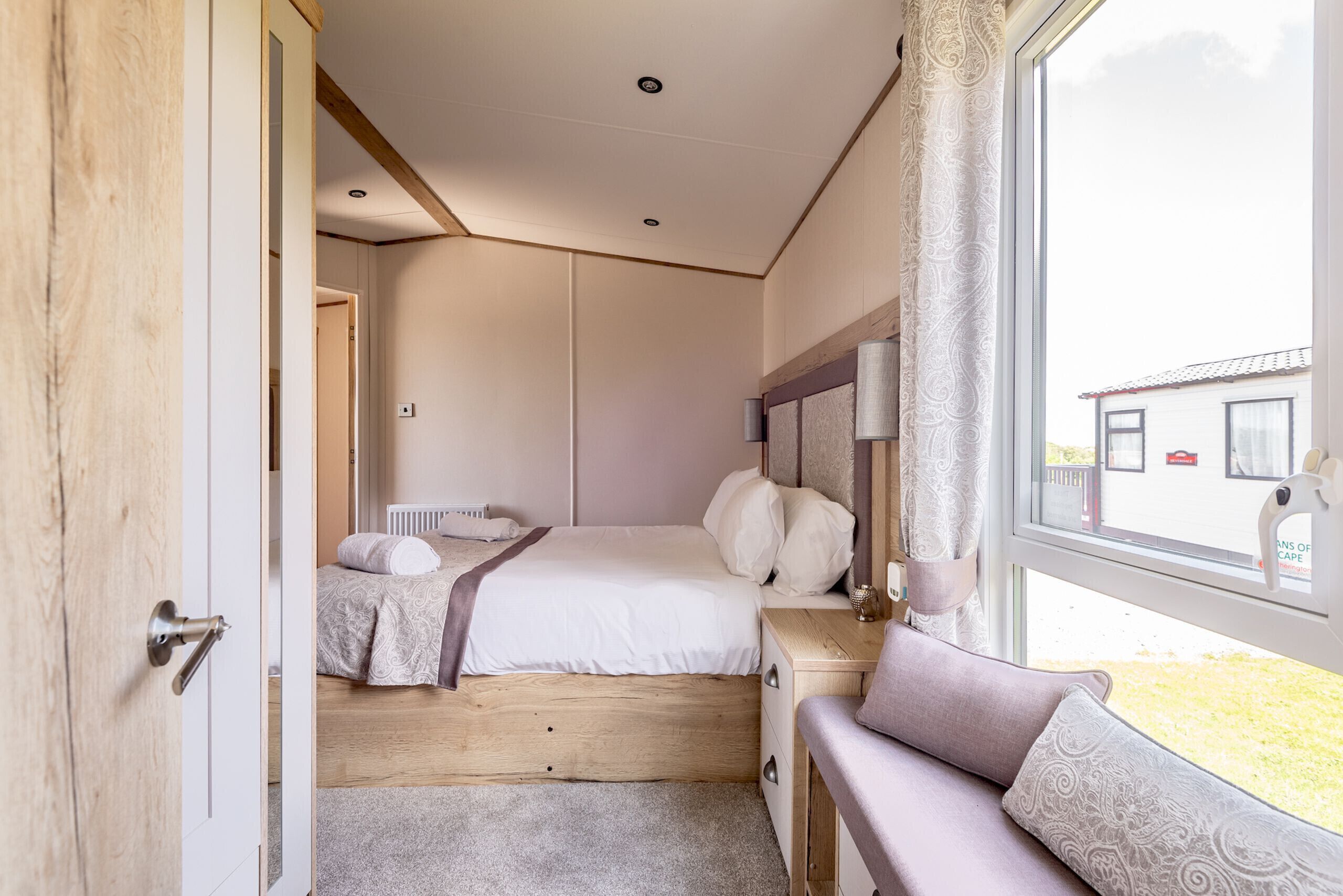 Una camera da letto con un letto, un comodino e una finestra vista su un edificio.