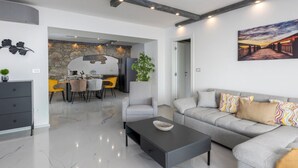 Un soggiorno moderno con un divano grigio, un tavolino da caffè e un'area pranzo con parete in pietra e sedie gialle.