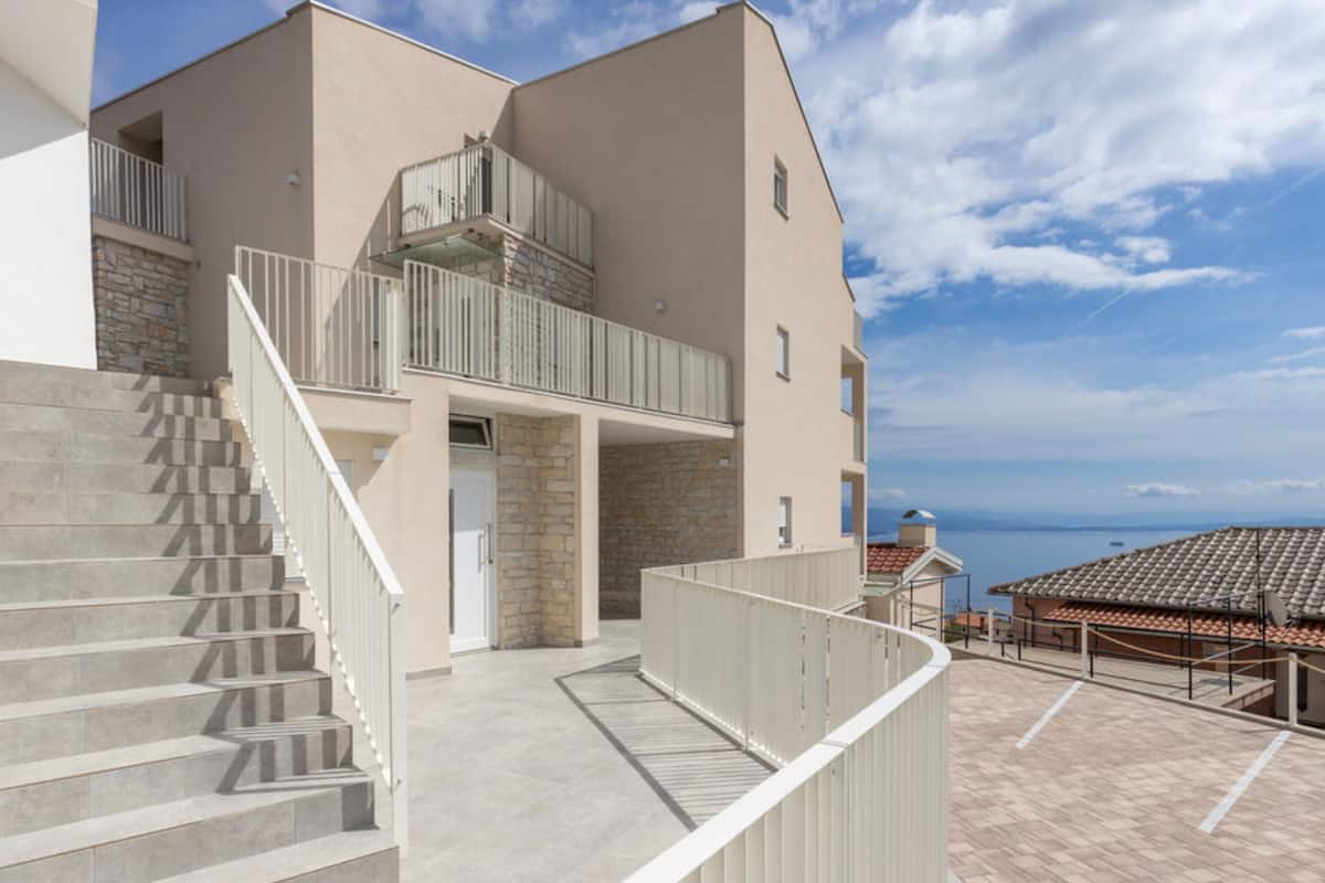 A modern building with a stone facade, a balcony, and a staircase leading to an upper level.