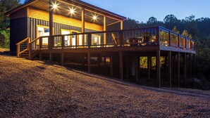 A two-story house with a deck, wooden exterior, and multiple windows.
