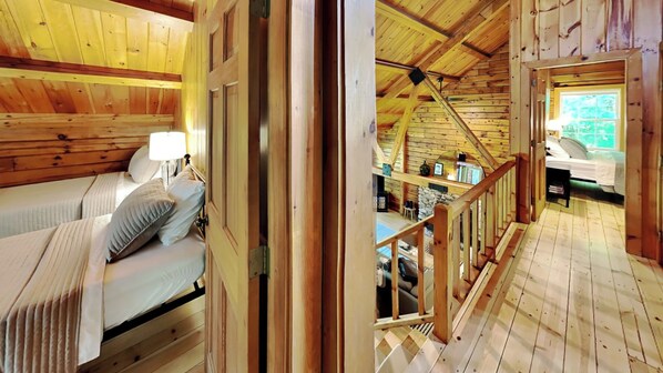 Une cabane en bois avec une chambre à l’étage, un escalier et une vue sur l’extérieur.