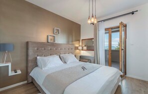 A bedroom with a large bed, a bedside table with a lamp, a nightstand, and a view of the outdoors through a sliding door. - Villa Anima in Pazin (Pazin)