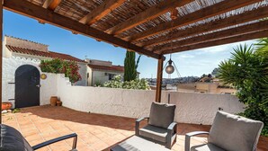 An outdoor patio with a pergola, seating area, and a view of the cityscape. - Paco Romo (Nerja)