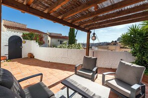 An outdoor patio with a pergola, seating area, and a view of the cityscape. - Paco Romo (Nerja)
