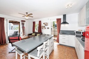 A modern kitchen with a central island, white cabinetry, and a ceiling fan. - Paco Romo (Nerja)