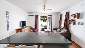 A modern kitchen with a central island, a dining area with chairs, a sofa, and a TV. - Paco Romo (Nerja)
