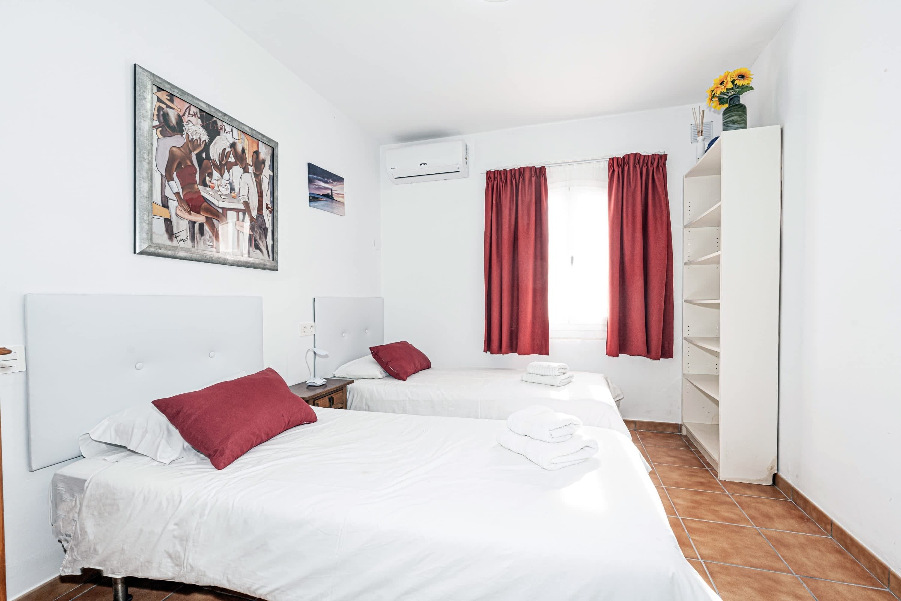 Ett hotellrum med två sängar, en garderob, en tavla och en luftkonditioneringsanläggning.