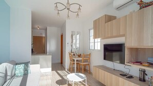A modern living room with a sofa, a dining table, and a TV. - Edf Papillon (Nerja)