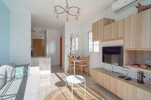 A modern living room with a sofa, a dining table, and a TV.