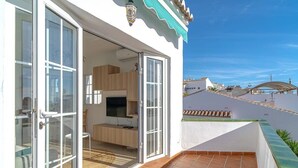 A residential building with a balcony, a sliding glass door entrance, a television, and a tiled floor. - Edf Papillon (Nerja)