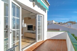 A residential building with a balcony, a sliding glass door entrance, a television, and a tiled floor.