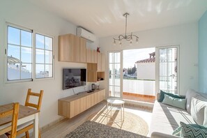 A modern living room with a TV, wooden furniture, a balcony with a view, and a chandelier. - Edf Papillon (Nerja)