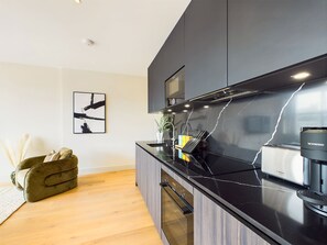 Una cocina moderna con encimera negra, una cafetera Nespresso Bosch y un diseño minimalista.