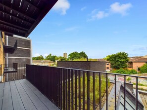 Ein Balkon mit Blick auf ein Wohngebiet, eine Backsteingemäuer und einen klaren Himmel.