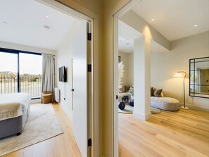 A modern bedroom with a bed, a TV, and a large window.