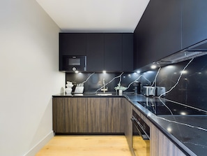 A modern kitchen with dark cabinetry, a built-in microwave, and a sleek countertop.