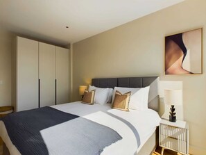 A hotel room with a bed, bedside tables, a wardrobe, and a painting on the wall.
