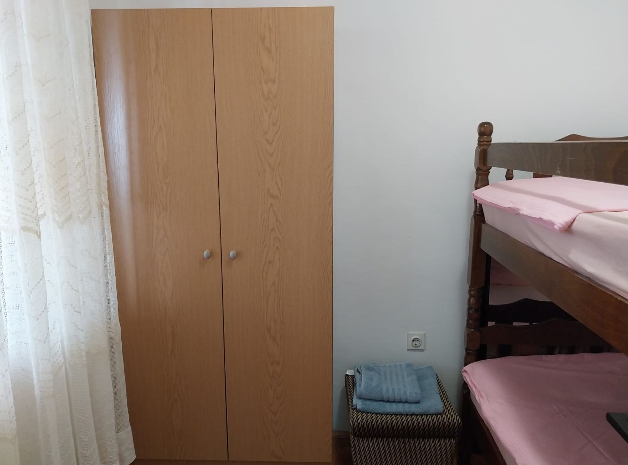 Un dormitorio con un armario de madera, una cama litera y una silla pequeña con una toalla.