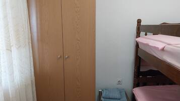 Un dormitorio con un armario de madera, una cama litera y una silla pequeña con una toalla.