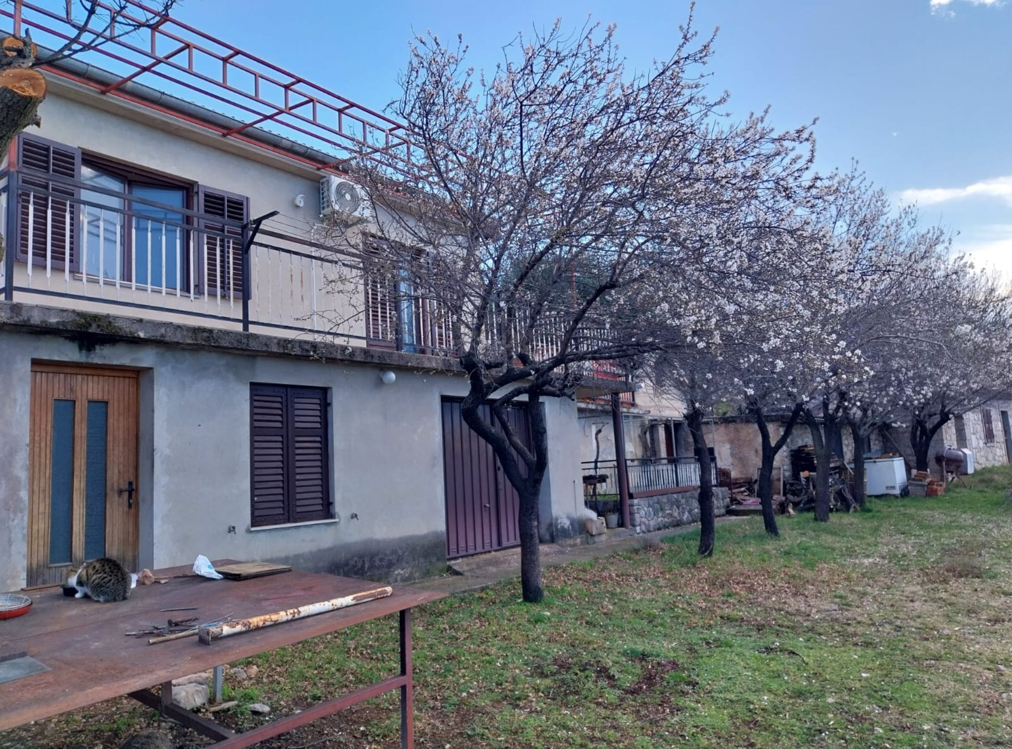 Ein Wohngebäude mit Balkon, einer Holztür und einem Tisch mit Gegenständen darauf.