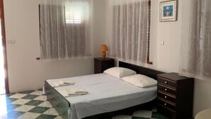 A bedroom with a bed, a nightstand, a dresser, and a window with sheer curtains. - Apartments Ata (Razanac)