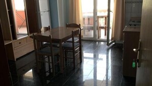 A compact kitchen with a dining table and chairs, a refrigerator, and a sliding glass door leading to a balcony. - Apartments Ata (Razanac)