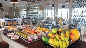 A buffet with a variety of fruits and a wine rack in the background. - Vila Galé Collection Sunset Cumbuco (Caucaia)