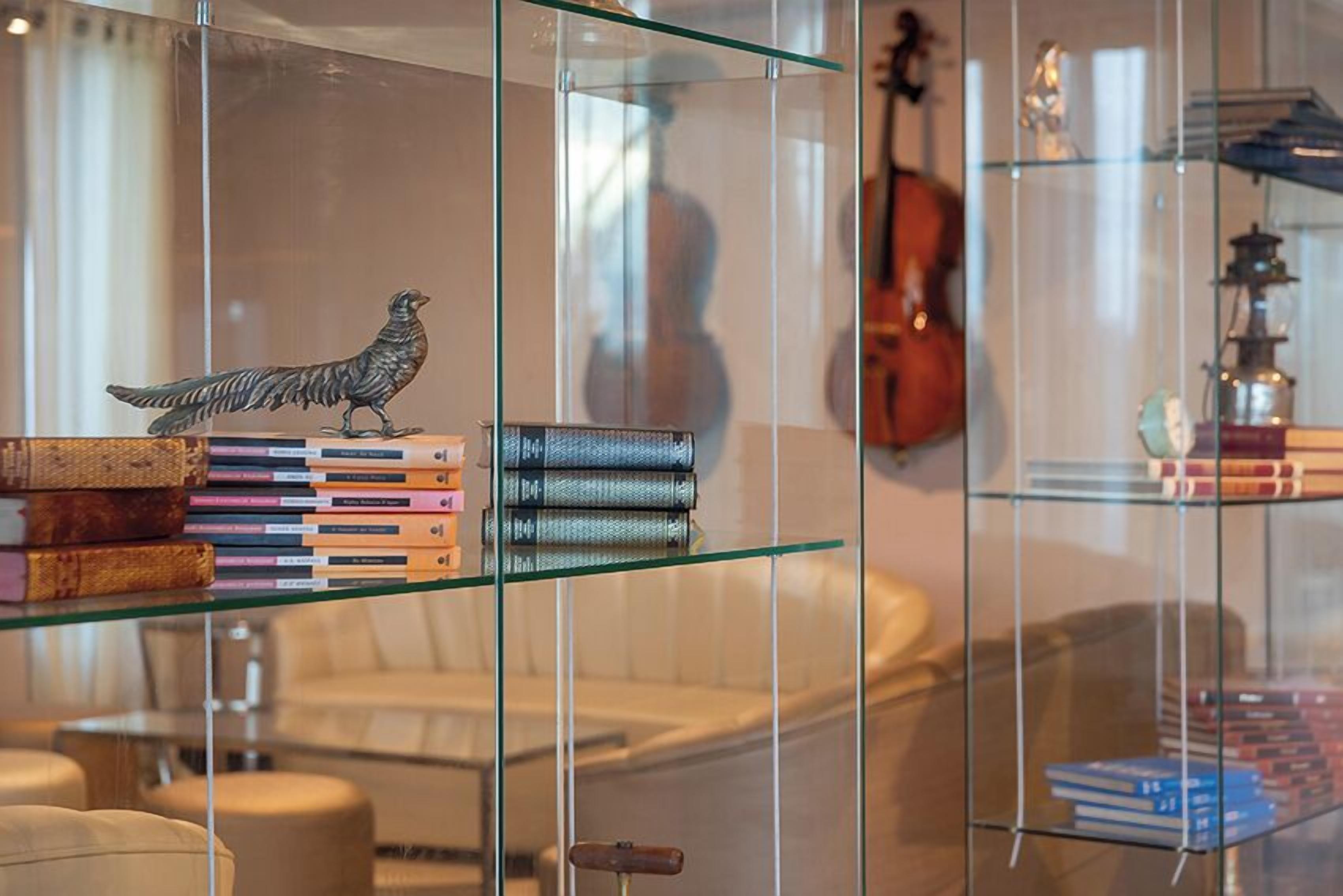 Una sala de estar moderna con un separador de vidrio, un violín y libros en estanterías.
