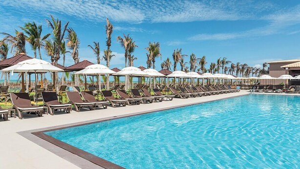A poolside area with sun loungers and umbrellas, surrounded by palm trees. - Vila Galé Collection Sunset Cumbuco (Caucaia)