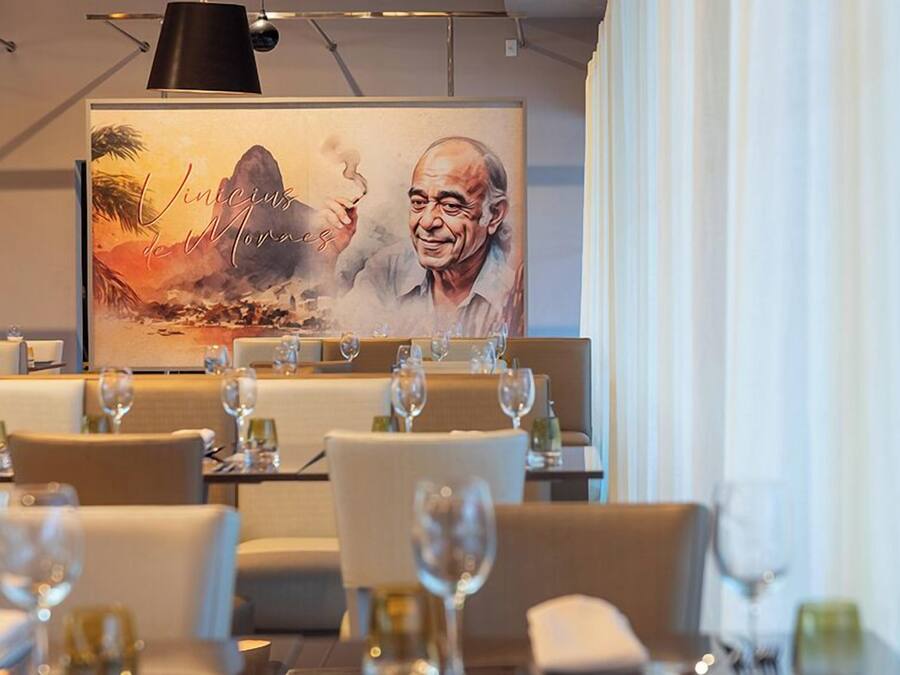 Un ristorante con tavoli apparecchiati, un quadro di grandi dimensioni appeso al muro e una lampada a sospensione moderna.